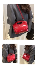 Detail of red glossy patent leather tote showing cutout handles and detachable shoulder strap