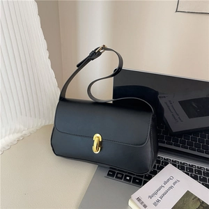 Classic black leather underarm bag with gold twist lock on a minimalist desk setup
