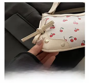 Close-up of cherry pattern handbag featuring precision stitching and bow detail