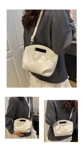 Detail of cream white patent leather bucket bag with cut-out handle and logo print