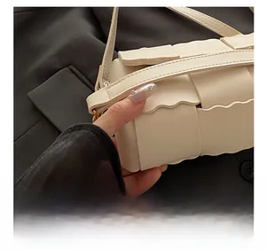 Close-up of cream woven shoulder bag featuring scalloped edges and precision stitching