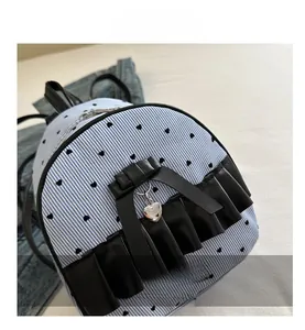 Detail of blue striped bow backpack with black heart patterns and silver pendant