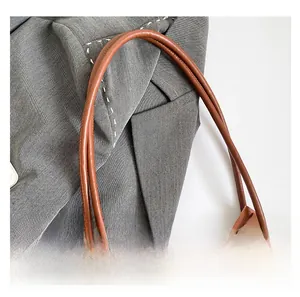 Detailed close-up of the tubular leather handles and monogram pattern on a brown tote