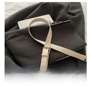 Detailed close-up of adjustable shoulder strap with silver buckle on ivory shoulder bag