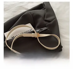 Detail of adjustable cream leather shoulder strap with gold buckle on a suit jacket