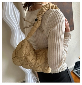Detail of khaki quilted puffer shoulder bag with pleated strap on a fashion model