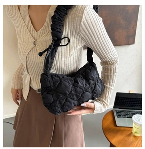 Detail of black quilted cloud bag showing ruffled shoulder strap and bow ribbon tie