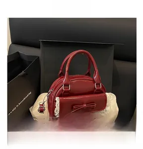 Detail of burgundy patent leather bowling bag with lace trim and bow in a gift box