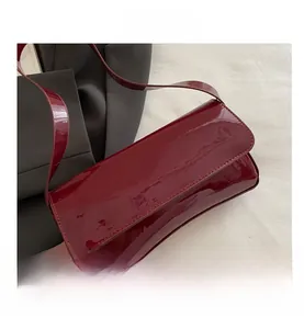 Detailed close-up of dark wine red patent leather shoulder bag with high gloss finish