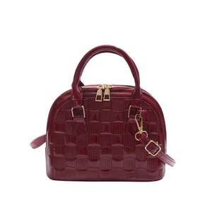 Glossy burgundy shell handbag with checkered texture and gold zippers on white background