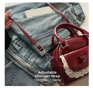 Detail of adjustable shoulder strap on burgundy patent leather bowling bag with lace trim