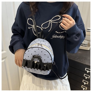 Detail view of light blue striped backpack with black heart dots and bow decoration