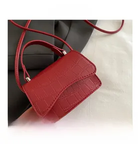 Vue détaillée du mini sac à main rouge texturé crocodile avec rabat et bandoulière