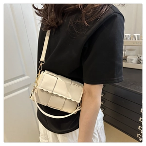 Detail of cream woven shoulder bag with wavy scalloped edges and gold chain strap