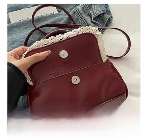 Detail view of burgundy shell bag with white lace trim and silver magnetic closure