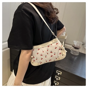 Detail of cherry print shoulder bag featuring metal rivet corners and side bow accent