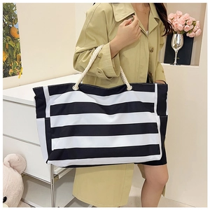 Close-up of large black and white striped canvas tote bag with thick white rope handles