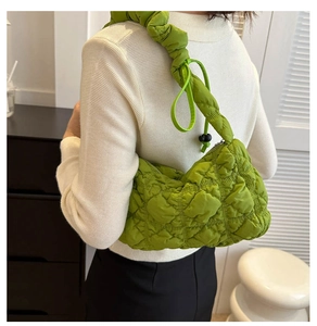Detail of a bright green quilted puff hobo bag with a stylish pleated shoulder strap