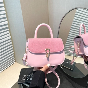 Sac à bandoulière rose minimaliste avec rabat tissé et boucle dorée tenu à la main