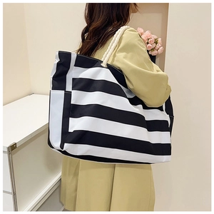 Detail of canvas tote bag featuring black and white stripes and woven rope handles