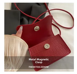 Détail d'un sac à main rouge texture crocodile avec fermeture magnétique en métal poli