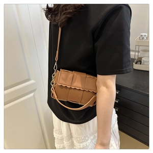 Close-up of brown woven leather crossbody bag featuring unique scalloped edge detail