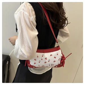 Side view of cherry print shoulder bag featuring red straps and tie-up details on model