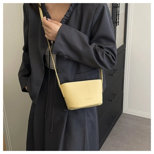 Detail of yellow lychee textured crossbody bag with FASHION lettering on model