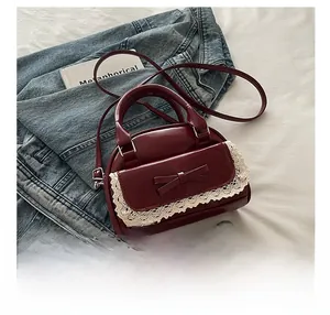 Detail of wine red bowling bag with lace trim, bow, and glossy finish on denim background