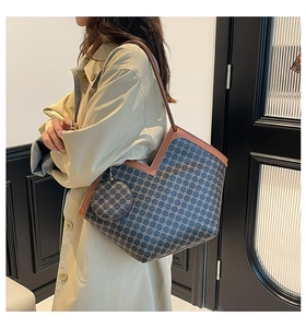 Detail of a large blue tote bag with geometric patterns worn by a model in a beige trench coat