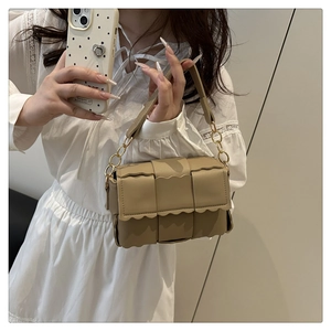 Close-up of woven leather crossbody bag featuring scalloped flap and gold chain strap