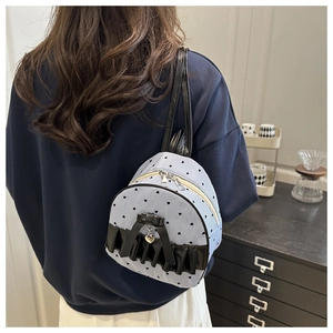 Close-up of mini blue striped backpack with black bows and heart pendant detail