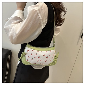 Detail of cherry print shoulder bag with green trim and drawstring side accents
