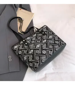 Detail of floral embroidery on black fabric tote with premium leather handles