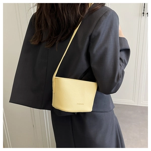 Detail of yellow litchi grain bucket bag with FASHION logo worn over the shoulder