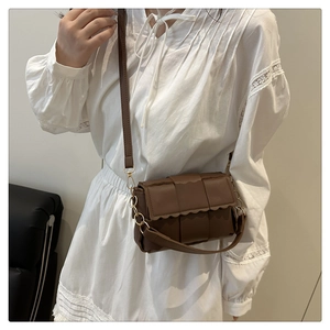 Détail du sac bandoulière tressé marron foncé avec rabat festonné et chaîne dorée