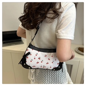 Detail of cherry print shoulder bag with black contrast trim and side bow decor
