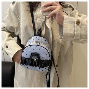 Mini backpack with blue stripes and black heart patterns shown on a beige coat