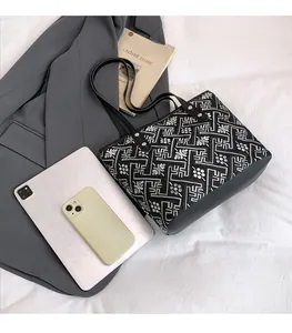 Detailed view of black and white vintage embroidered tote bag with size comparison to iPad