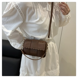 Detailed view of woven leather crossbody bag with wavy edges and golden hardware