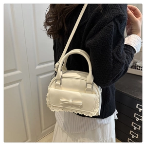 Lace-trimmed retro crossbody bag with 3D bow detail shown in a casual lifestyle scene