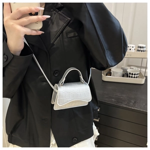 Model wearing a mini silver croc-embossed square crossbody bag with a slim strap