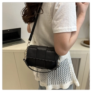 Detail of black woven leather crossbody bag with scallop trim and gold metal hardware