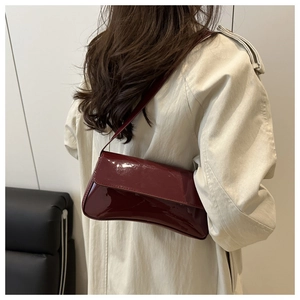 Rear view of a model wearing the dark red patent leather baguette bag over a beige coat