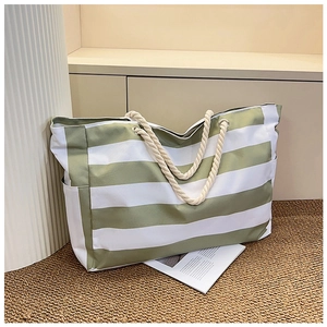 Detail of green striped canvas tote bag showing thick cotton rope handles and metal eyelets