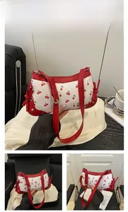 Detail of white cherry print saddle bag with red trim, silver chain, and bow accents