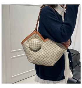 Detail view of monogram tote bag with brown leather V-trim and round coin purse attachment