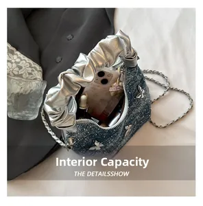 Detail view showing interior capacity of a denim handbag with butterfly chain decoration