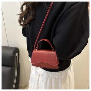 Détail d'un mini sac rouge à motif crocodile avec poignée et bandoulière amovible