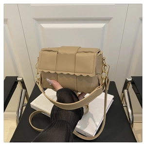Detail of beige woven PU leather crossbody bag with wavy edge and gold chain lock